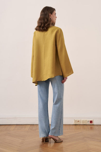 Cherianne.com wheat-colored linen blouse with wide bell sleeves and asymmetrical hem worn by a model with jeans.