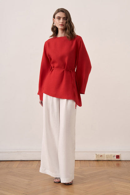Cherianne.com red linen blouse with wide sleeves and waist tie paired with white wide-leg linen trousers on a model