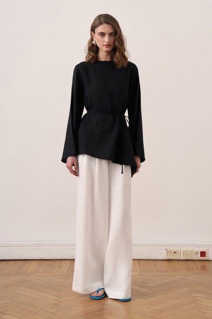 Cherianne.com black linen blouse with wide sleeves and waist tie, paired with white wide-leg trousers on a model.