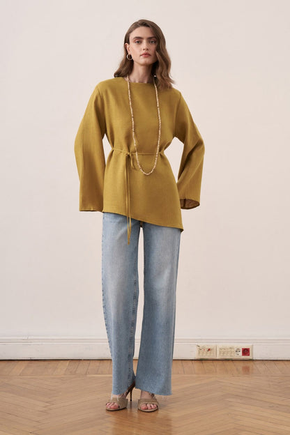 Cherianne.com wheat-colored linen blouse with wide bell sleeves and asymmetrical hem worn by a model with jeans.