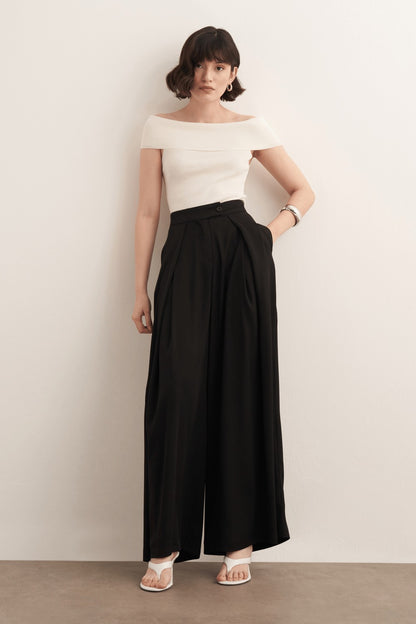 Cherianne.com model wearing black high-waisted wide-leg trousers with a ruffled design and side pockets
