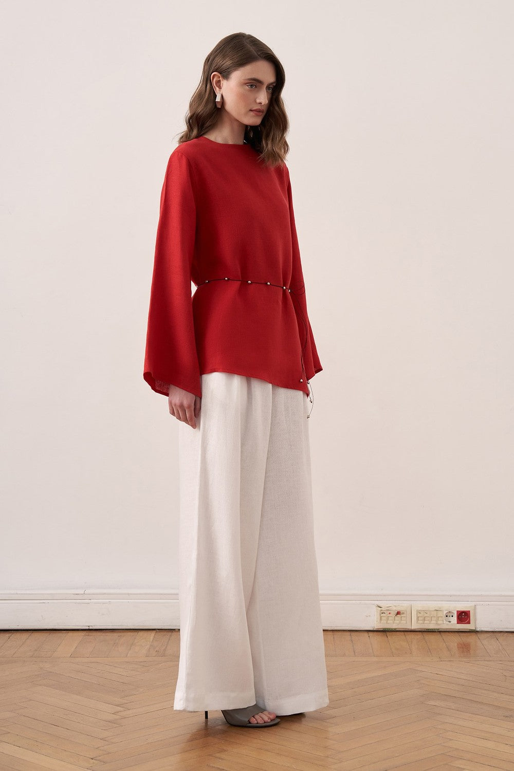 Cherianne.com red linen blouse with wide sleeves and waist tie paired with white wide-leg linen trousers on a model