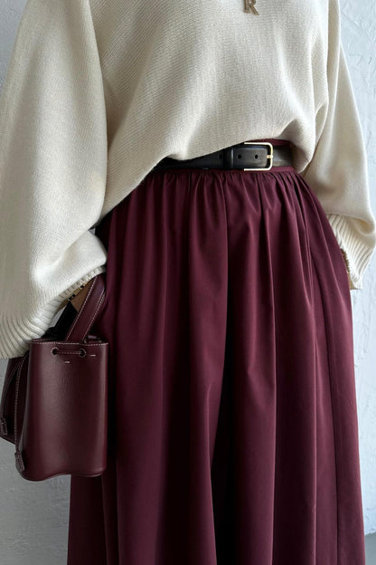 Cherianne.com burgundy poplin flared skirt with pockets, styled with a cream knit sweater and black belt.