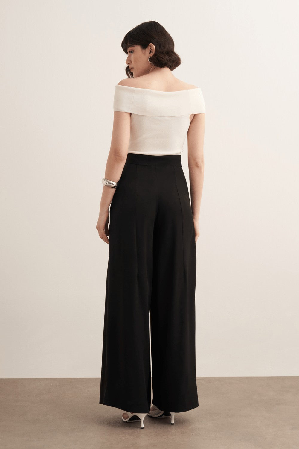 Cherianne.com model wearing black high-waisted wide-leg trousers with a ruffled design and side pockets