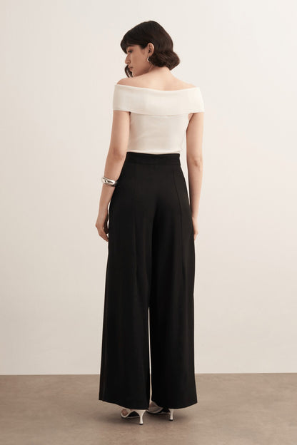 Cherianne.com model wearing black high-waisted wide-leg trousers with a ruffled design and side pockets