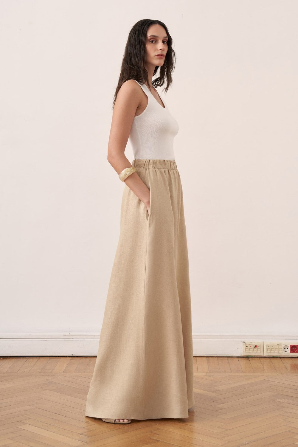 Cherianne.com beige wide-leg linen trousers with an elasticated waistband worn by a model with a white tank top