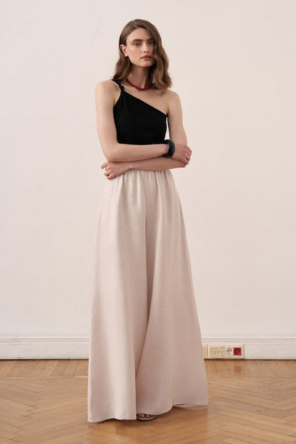 Model wearing Cherianne.com beige wide-leg linen trousers with an elasticated waist and a black one-shoulder top.