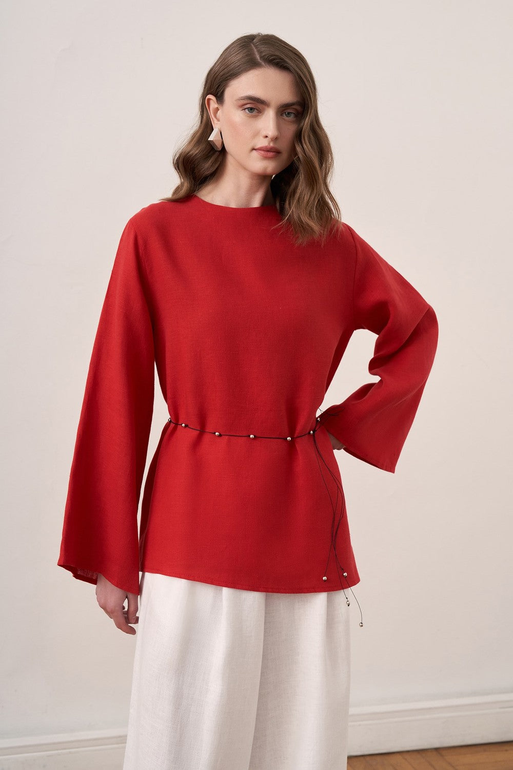 Cherianne.com red linen blouse with wide sleeves and waist tie paired with white wide-leg linen trousers on a model