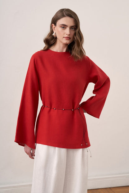 Cherianne.com red linen blouse with wide sleeves and waist tie paired with white wide-leg linen trousers on a model