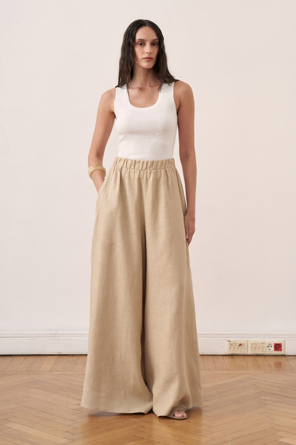 Cherianne.com beige wide-leg linen trousers with an elasticated waistband worn by a model with a white tank top
