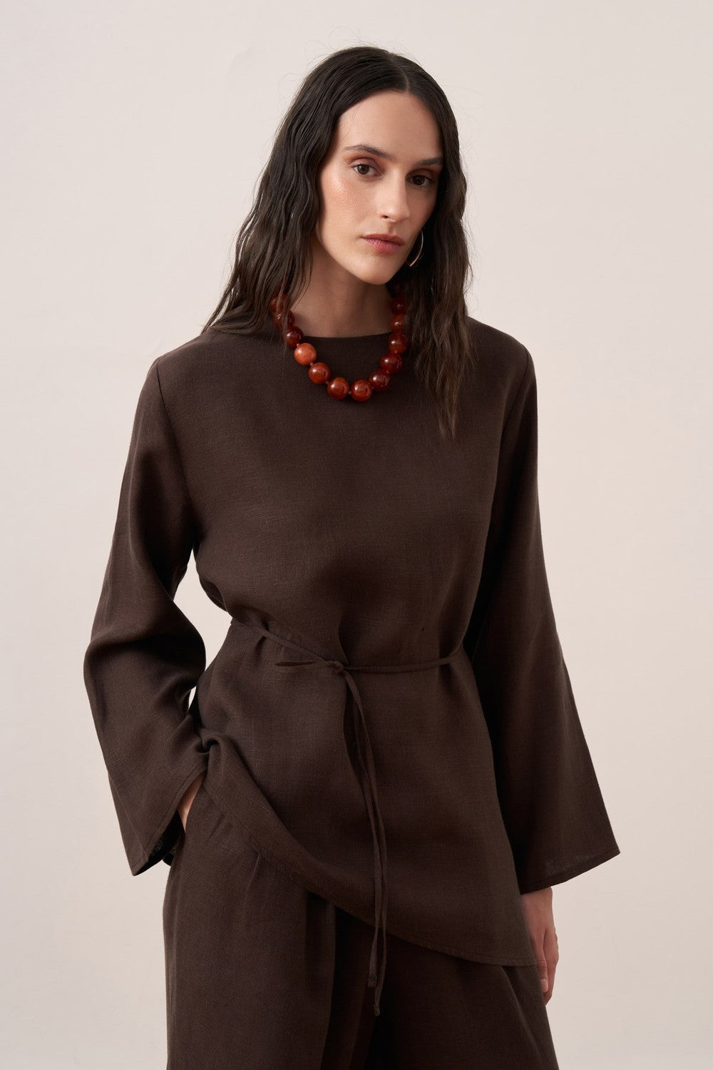 Cherianne.com dark brown linen blouse with wide sleeves, crew neck, and adjustable waist tie on a model.