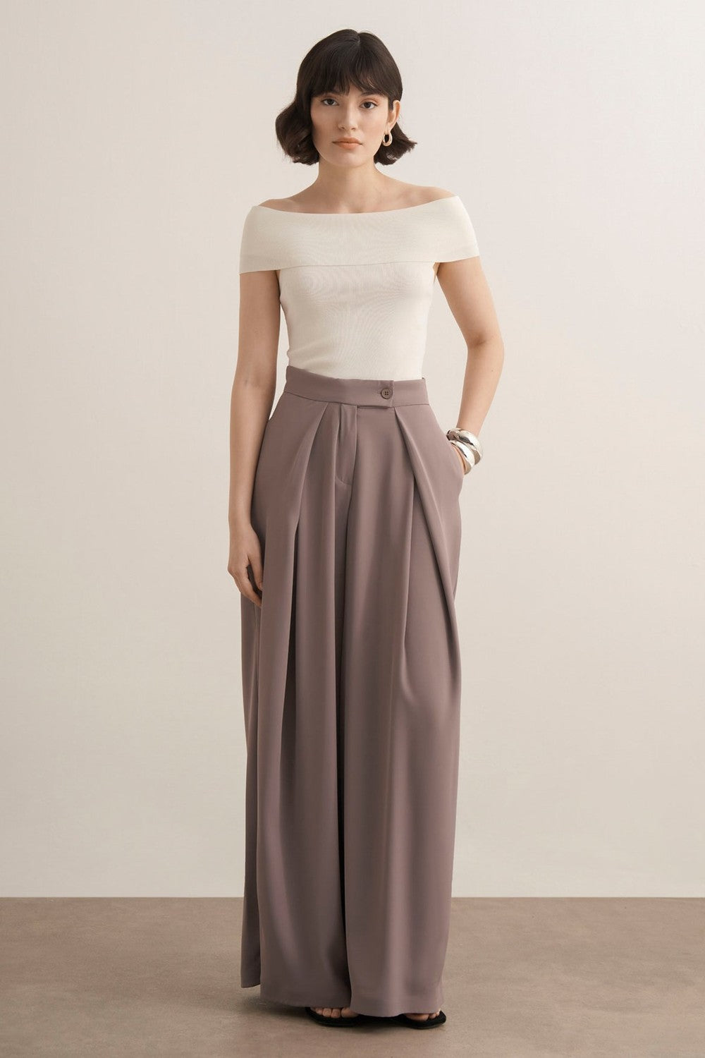 Cherianne.com Leona high-waisted wide-leg trousers in taupe with pleated details and side pockets on a model.