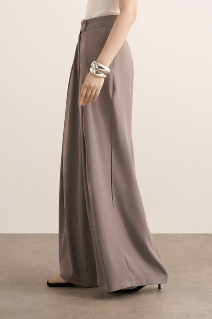 Cherianne.com Leona high-waisted wide-leg trousers in taupe with pleated details and side pockets on a model.