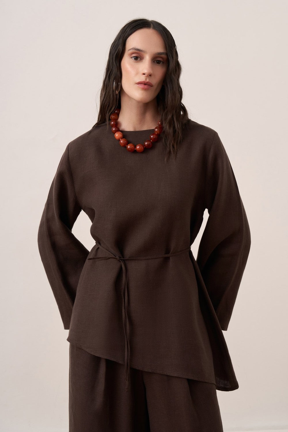 Cherianne.com dark brown linen blouse with wide sleeves, crew neck, and adjustable waist tie on a model.