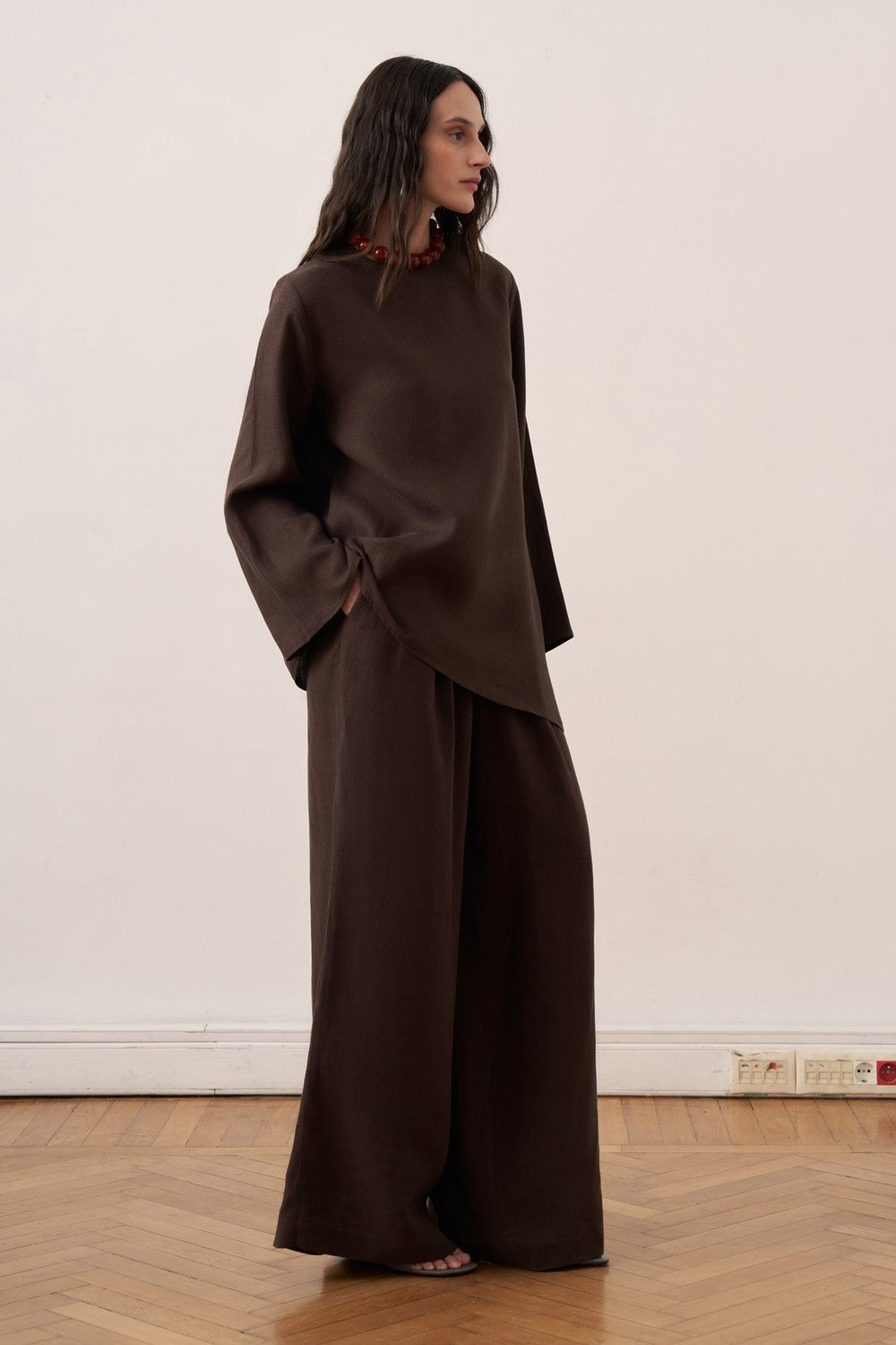 Cherianne.com dark brown linen blouse with wide sleeves, crew neck, and adjustable waist tie on a model.