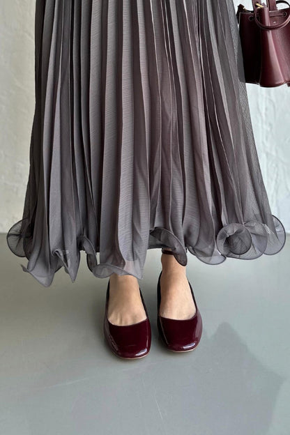 Cherianne.com gray pleated maxi chiffon skirt with a ruffled hem, paired with dark burgundy patent leather flats.