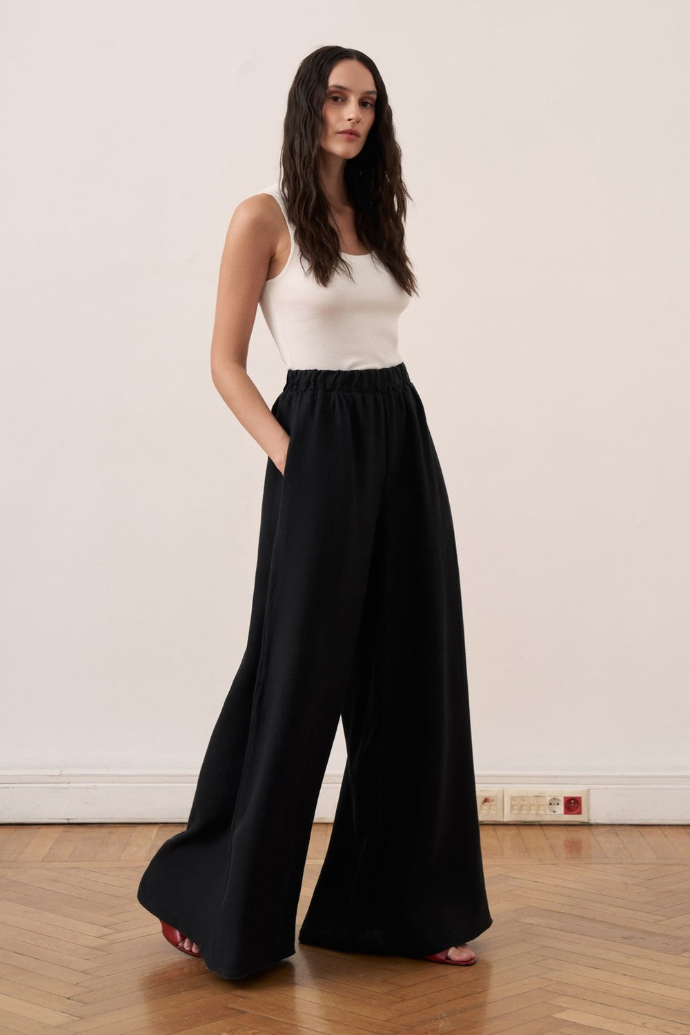Cherianne.com black wide-leg linen trousers with an elasticated waist and side pockets worn by a model.