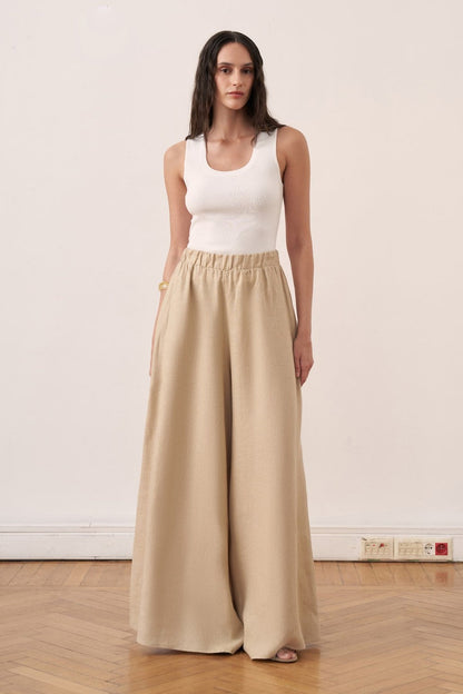 Cherianne.com beige wide-leg linen trousers with an elasticated waistband worn by a model with a white tank top
