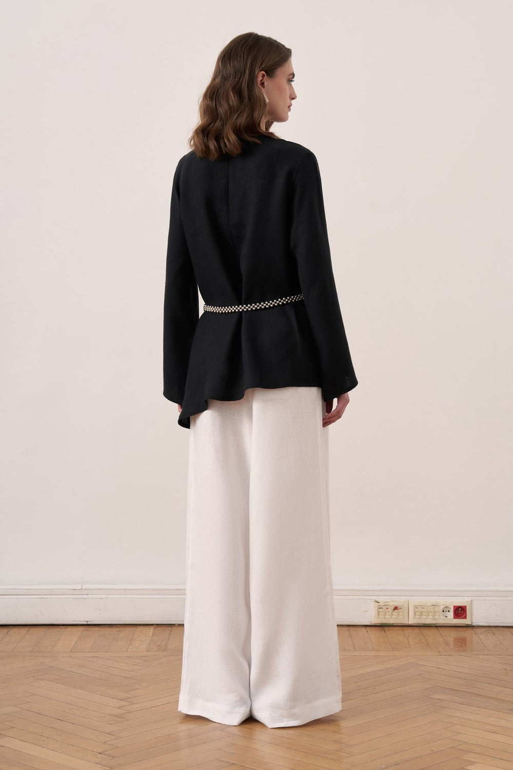 Cherianne.com black linen blouse with wide sleeves and waist tie, paired with white wide-leg trousers on a model.