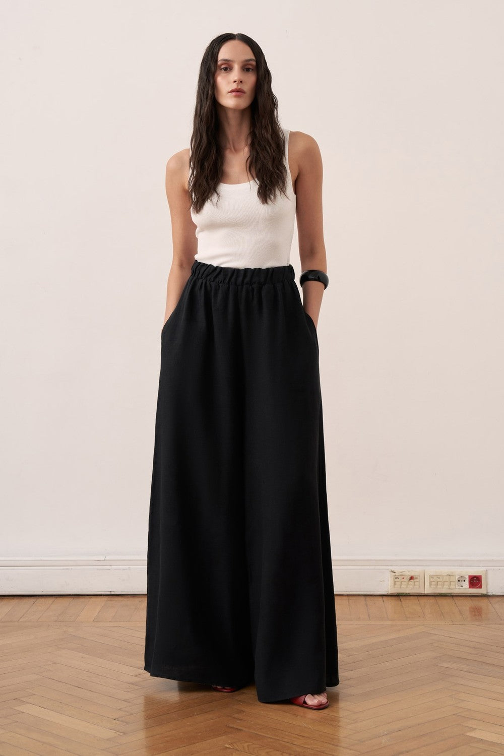 Cherianne.com black wide-leg linen trousers with an elasticated waist and side pockets worn by a model.