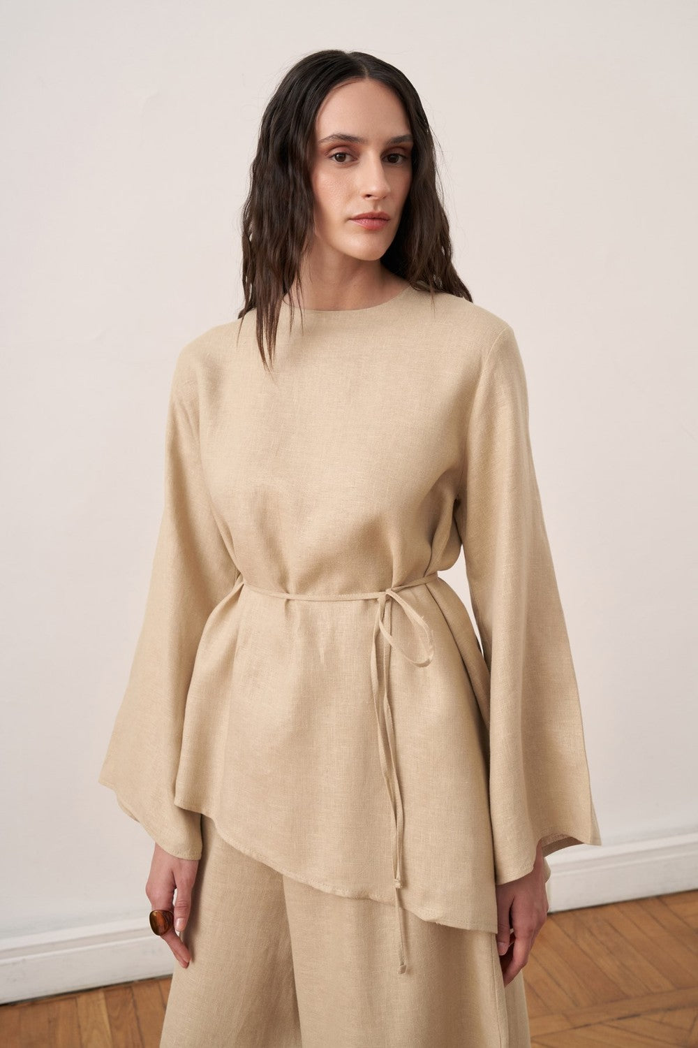 Cherianne.com wheat beige linen blouse with wide bell sleeves, crew neck, and adjustable waist tie on a model