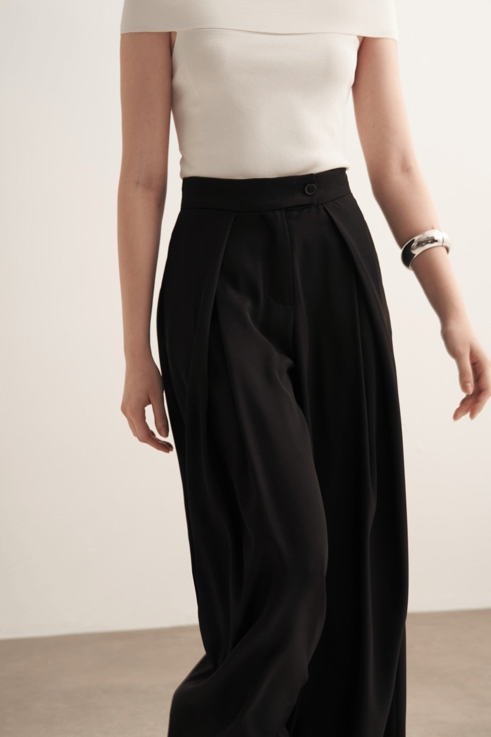 Cherianne.com model wearing black high-waisted wide-leg trousers with a ruffled design and side pockets