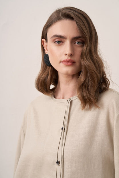 Cherianne.com beige linen shirt with mandarin collar, asymmetric button placket, and long sleeves on a model.