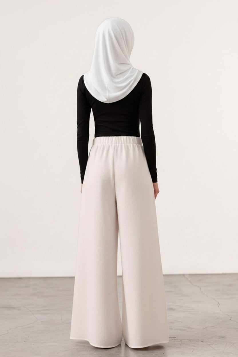 Cherianne.com beige wide-leg linen trousers with an elastic waistband worn by a model in a black top and white hijab.