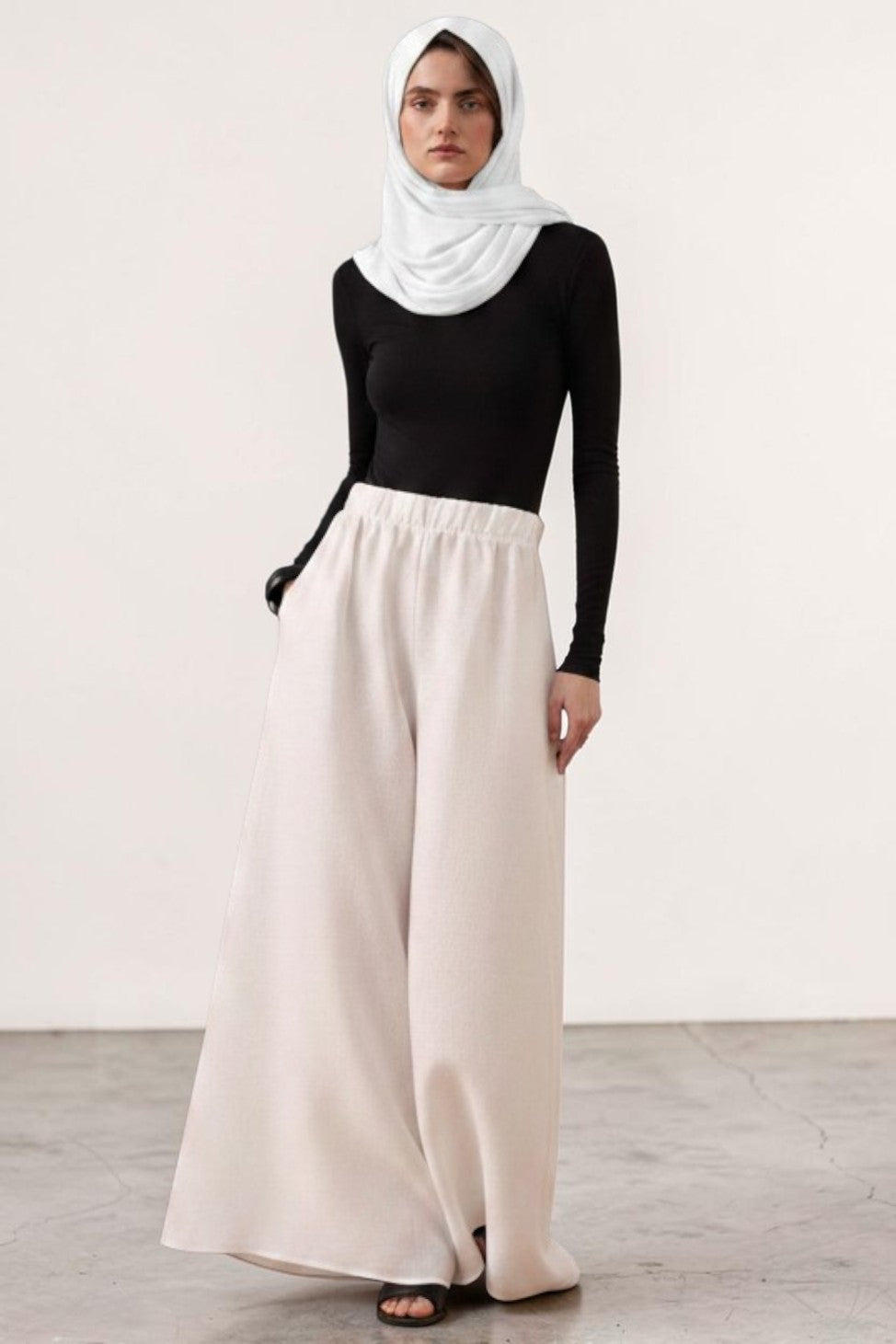 Cherianne.com wide-leg beige linen trousers with an elastic waistband, worn by a model in a black top and white hijab.