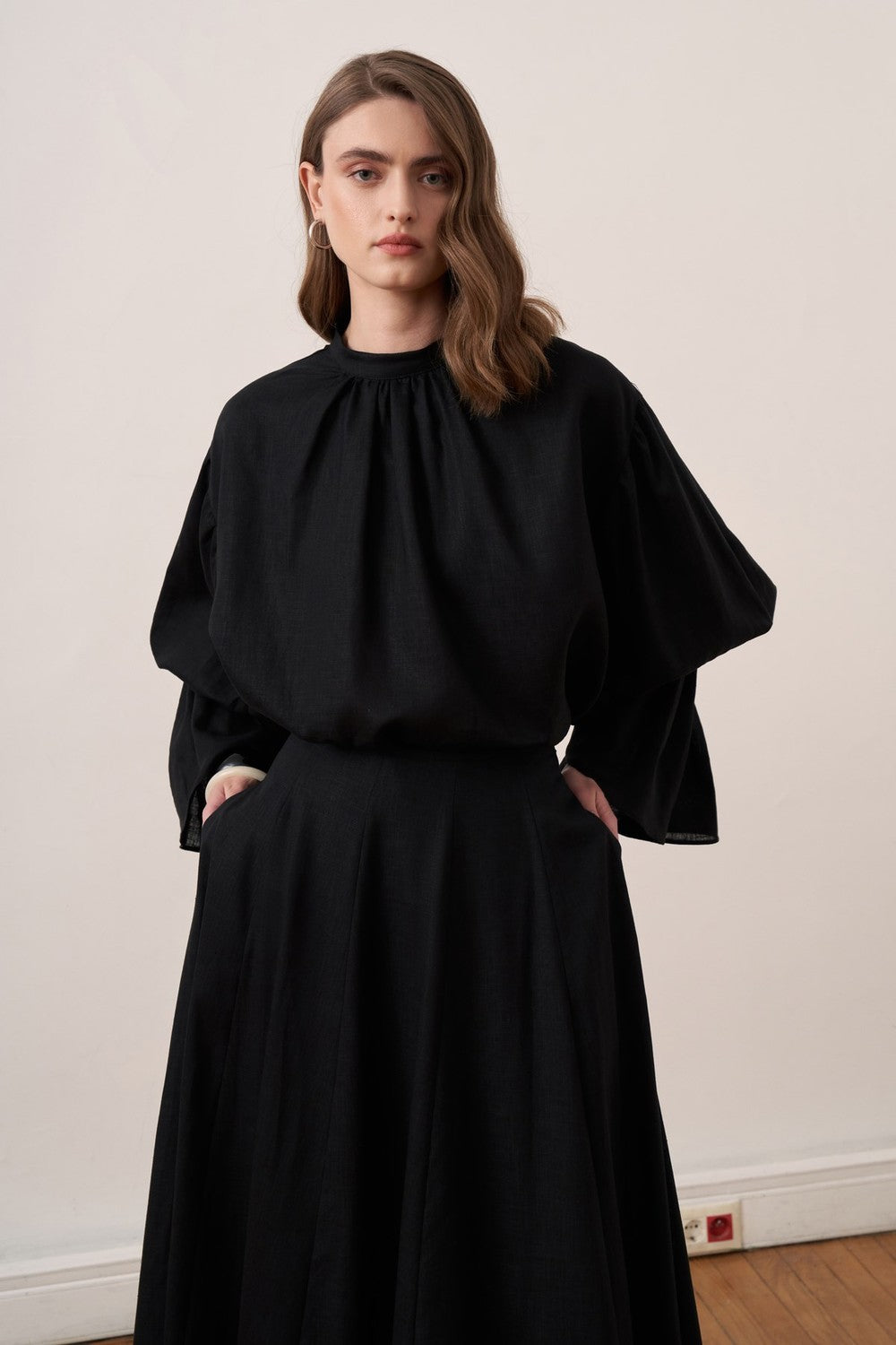 Cherianne.com black linen blend blouse with voluminous balloon sleeves and a minimalist gathered mock neck collar.