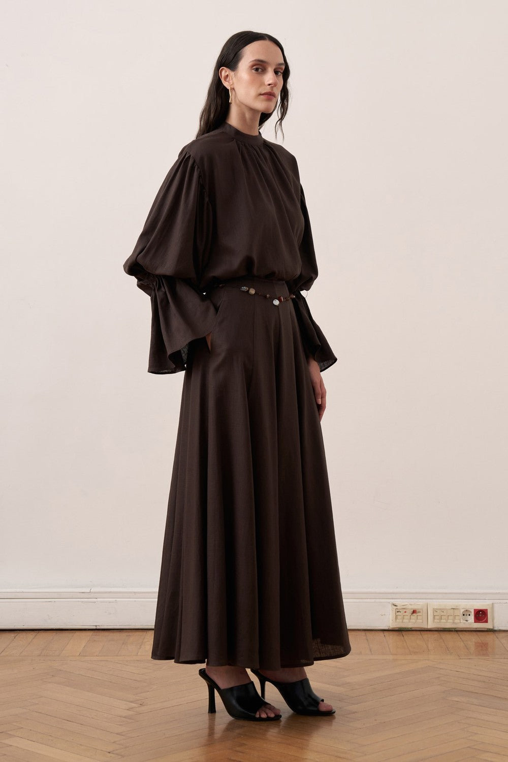 Cherianne.com dark brown linen blend blouse with voluminous balloon sleeves and gathered high neck detail on a model.