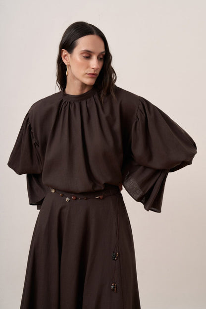 Cherianne.com dark brown linen blend blouse with voluminous balloon sleeves and gathered high neck detail on a model.