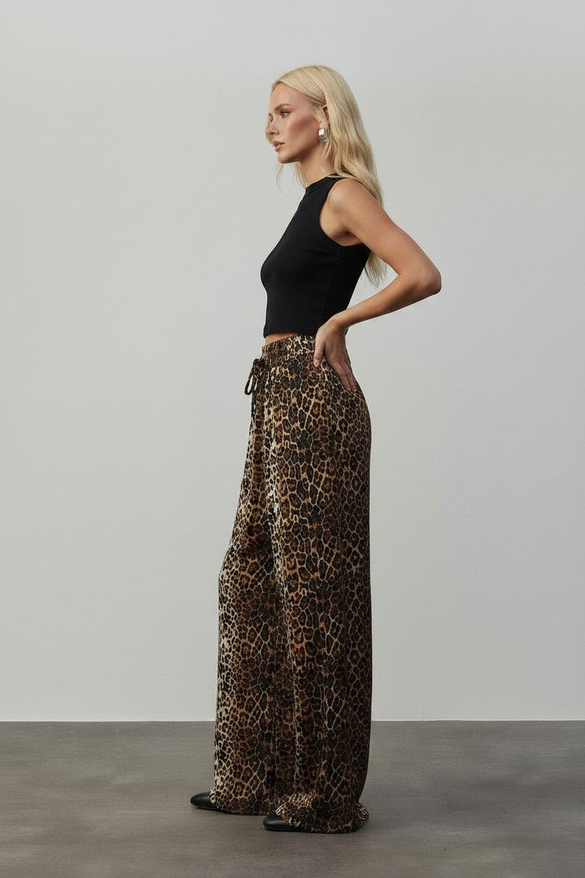 Cherianne.com brown leopard print satin wide leg trousers with an elasticated drawstring waist worn by a model.
