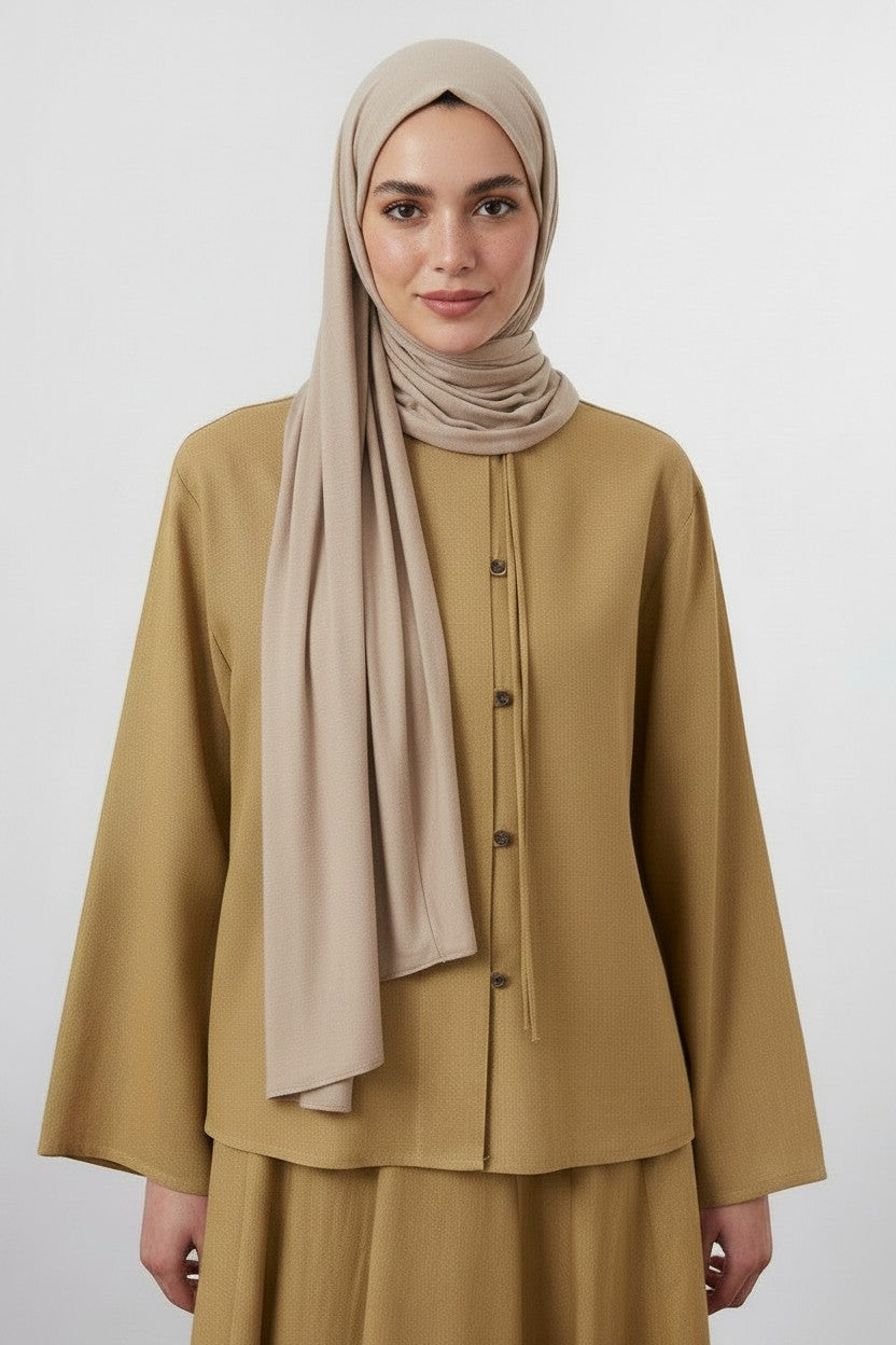 Model wearing a Cherianne.com mustard yellow linen-blend shirt with a mandarin collar and asymmetric button detail.