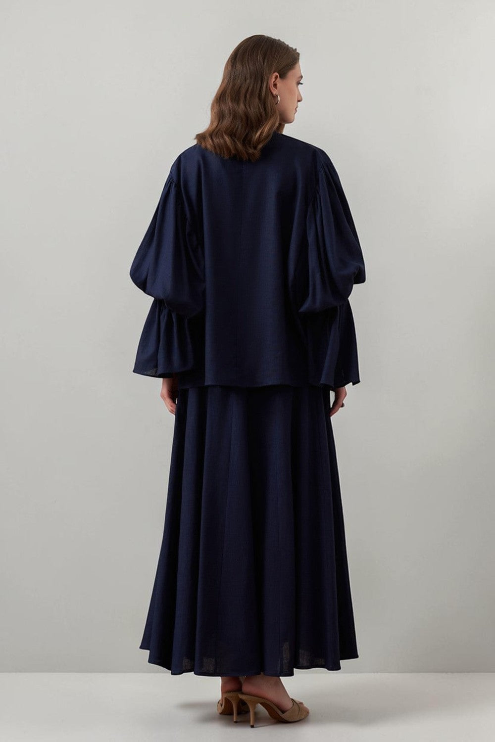 Cherianne.com navy blue linen-blend blouse with voluminous balloon sleeves and gathered cuffs, back view on model.