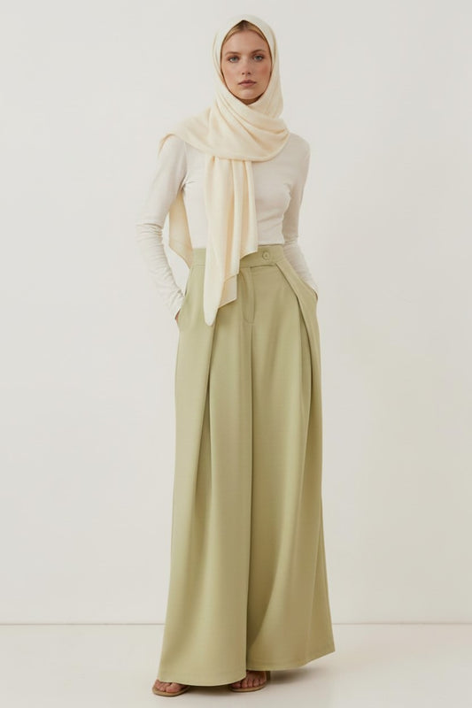 Cherianne.com high-waisted sage green wide-leg trousers with pockets worn by a model in a cream hijab and top.
