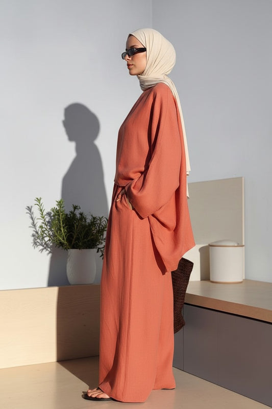 Cherianne.com terracotta oversized linen blouse with an asymmetric cut worn by a model in a minimalist studio setting