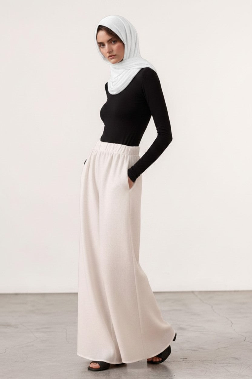 Model wearing Cherianne.com white wide-leg linen trousers with an elasticated waist and side pockets.