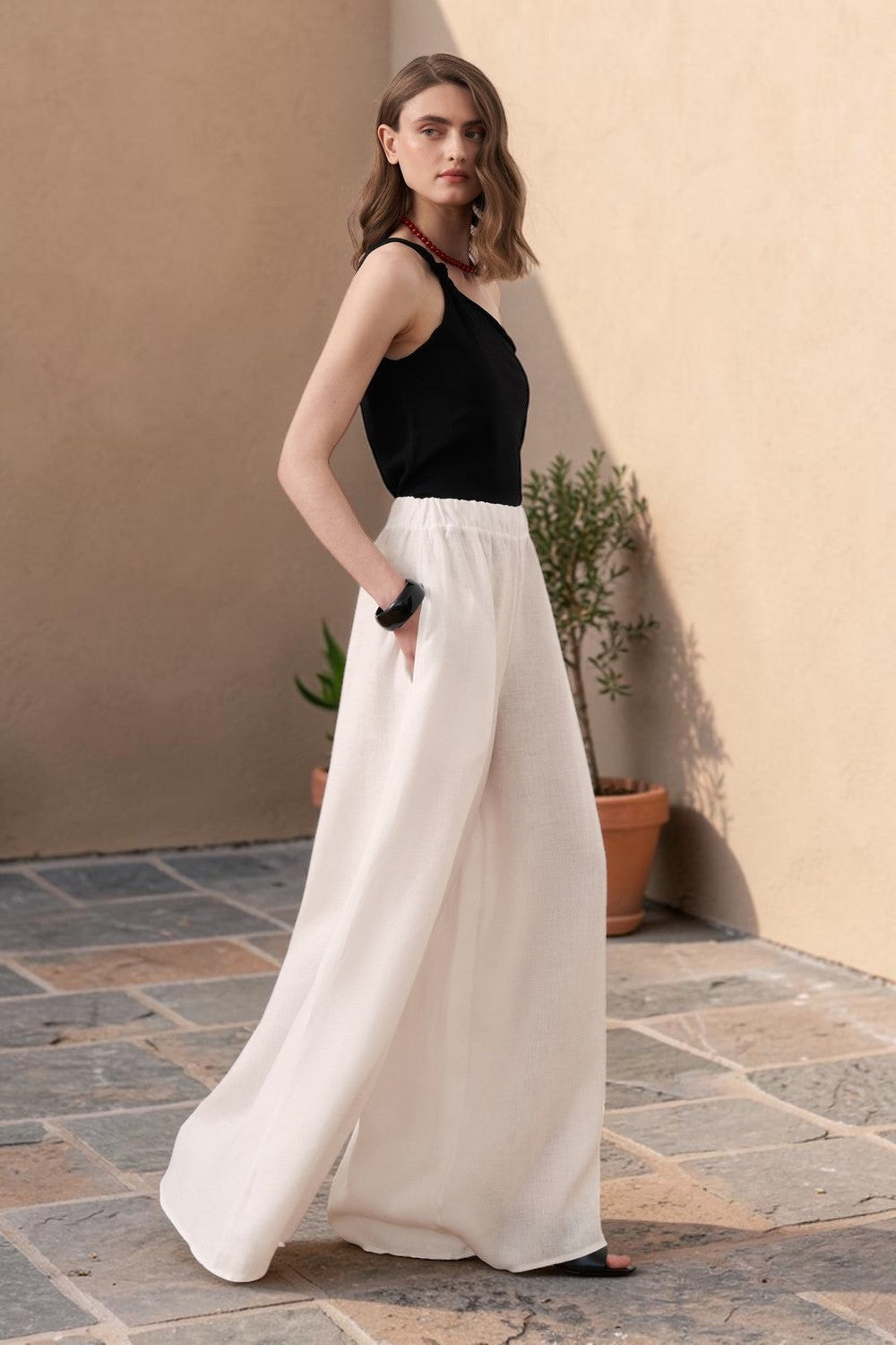 Cherianne.com white wide-leg linen trousers with an elasticated waist worn by a model in a studio setting
