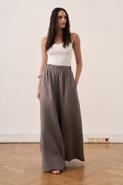 Cherianne.com wide-leg grey linen trousers with an elasticated waist worn by a model in a studio setting.